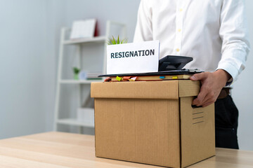 A businessman holds a box for personal items after sending a resignation letter to an executive or...