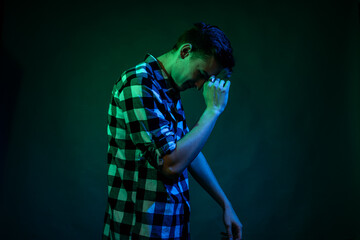 A young man dances in the studio with blue and green light