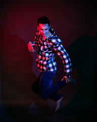 Fototapeta na wymiar A guy in a plaid shirt with red and blue lighting in the studio on a black background