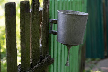 Metal washbasin hanging on an old wooden fence