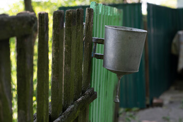 Metal washbasin hanging on an old wooden fence