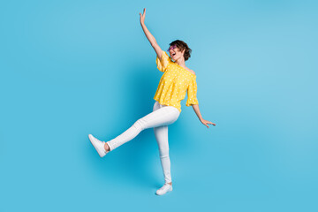 Full body profile side photo of cheerful brunette woman raise hands leg dance isolated on pastel blue color background