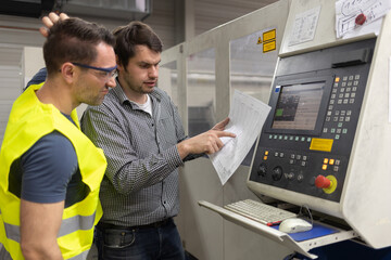 Arbeitsvorbereiter erklärt Bediener eine Laserschneidanlage den Ablaufplan