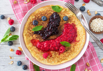 healthy breakfast pancake with oats served with fresh pureed berries on a plate