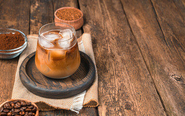 Summer drink, iced coffee with milk on a wooden background with coffee beans.