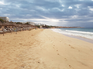 View of the sandy beach and hotels of the sea coast in Cyprus against the backdrop of a gloomy sky..