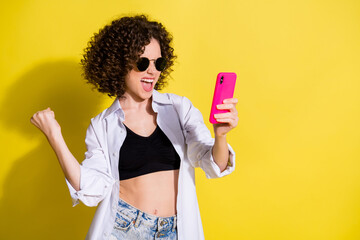 Photo portrait of female student keeping mobile phone gesturing like winner isolated on bright color background copyspace