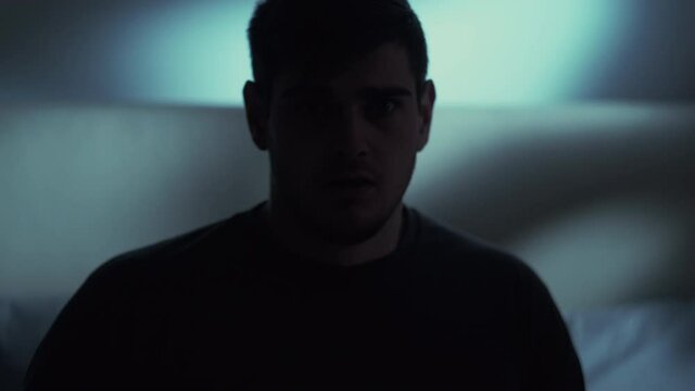 Night terror. Bad dream. Anxiety insomnia. Sleep disorder. Disturbed scared shocked man woke up from nightmare in bed late in dark home bedroom.