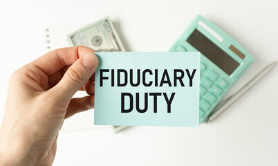 Text FIDUCIARY DUTY is written on a notebook with a pen and a magnifying glass lying on the table. Business concept.