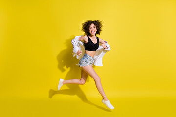 Fototapeta na wymiar Full size profile photo of optimistic cool girl run wear top shorts shirt sneakers isolated on yellow background