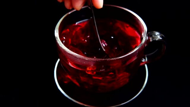 Preparation of Hibiscus tea in a glass cup.