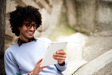 Fototapeta premium Young african businessman using tablet outdoors. Happy student learning outside.