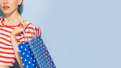 Happy shopping woman with shopping bags over blue background wearing striped clothing and shoping bags in patriotic colors