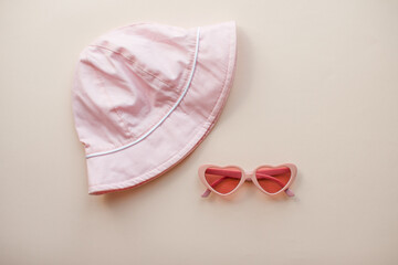 Layout. Pink heart-shaped glasses and a pink Panama hat on a light pink background. Summer. High quality photo