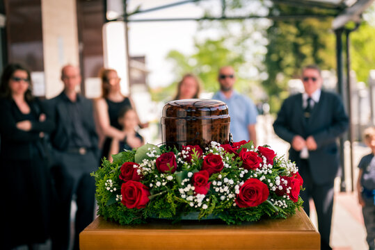 Funerary urn with ashes of dead and flowers at funeral.