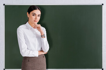 Teacher looking at camera near chalkboard