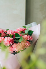 Delicate bouquet of coral carnations with eucalyptus greens with green bokeh. Summer background