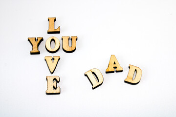 Wooden letters love you arranged in cross shape and letters "dad" in arch, isolated on white background