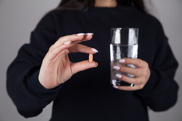 Woman with a glass of water in her hand and pill.