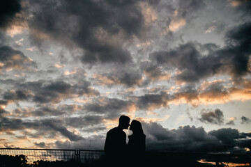 Silhouette of a young couple kissing at sunset with a storm in the background