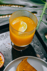 A glass of mango nectar with a slice of lime and cut passion fruit