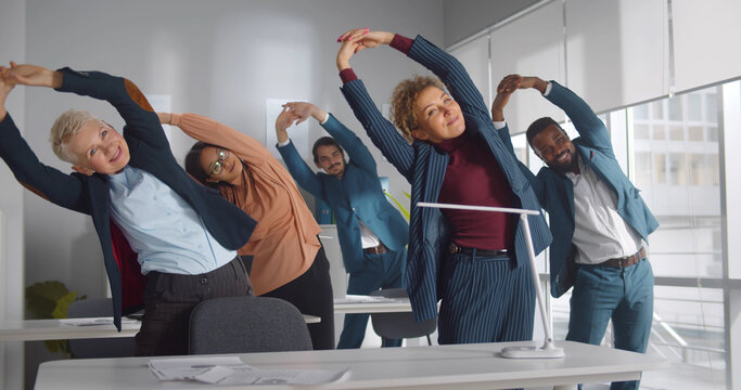 Group of happy diverse businesspeople doing stretching exercise in office