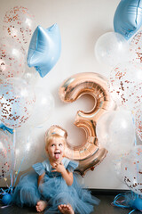 Birthday of a little blonde girl. Child in festive balloons. 