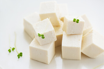 Pieces of tofu cheese with micro greens on a light background. Closeup, selective focus.