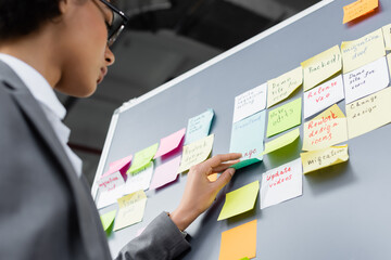 Low angle view of african american manager standing near board with sticky notes