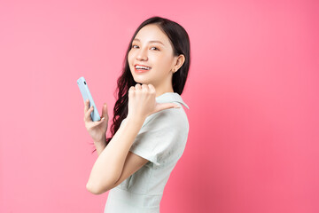 Young Asian woman holding phone in hand and pointing back