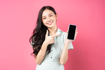 Young Asian woman holding phone in hand and pointing at it with playful expression - Powered by Adobe