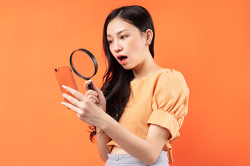 Woman holding a magnifying glass looking at her phone with a surprised expression