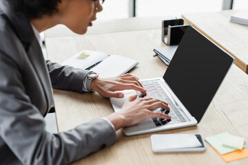 Cropped view of african american manager using laptop near cellphone on blurred foreground