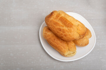 Air eclairs on white saucer. Close up, top view. Profiteroles, puffs or popovers.