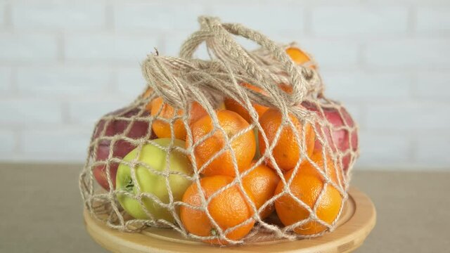 Natural fruits in a bag in the kitchen. A view of ripe colorful fruits in a fabric cotton mesh on the table.