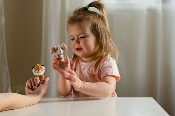 Little expressive girl playing theater with animal finger puppets. Role-playing games and...