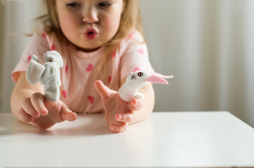 Little expressive girl playing theater with animal finger puppets. Role-playing games and...
