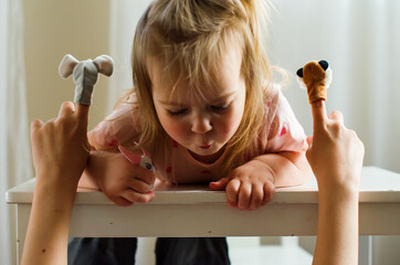 Child playing theater with animal finger puppets. Role-playing games and activities for expressing...