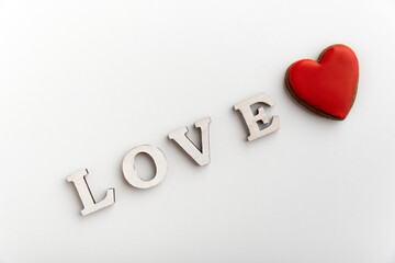 White inscription LOVE on white background next to red heart. Valentines day