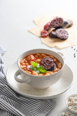 Asturiana traditional fabada with haricot, blood sausage on white table. Vertical orientation. Spanish cuisine. Close up.