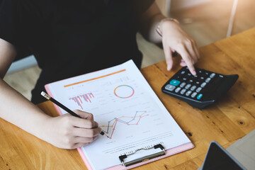 Business woman  using  document and using calculator to review balance sheet annual  to calculating...