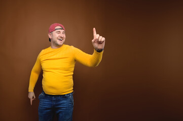 Naklejka premium A positive, overweight man in casual clothes throws his index finger up in a happy gesture having found an idea. Space to copy joy and happiness