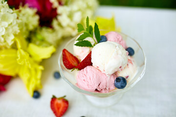 Tasty Ice cream and fresh blueberries, strawberry in the bowl, presented with flower