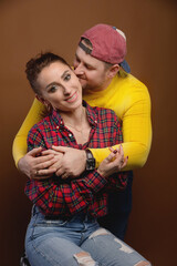 Caucasian married couple man and woman hugging and kissing eyes closed. Casual style and bright clothes of an ordinary 30-year-old couple studio portrait