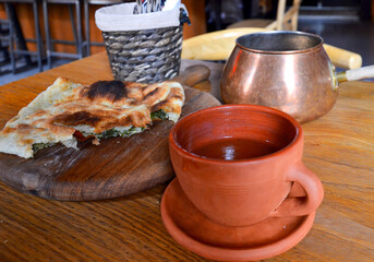 An invitation to tea. Freshly baked Georgian pie on a board, fragrant tea in a ceramic cup.