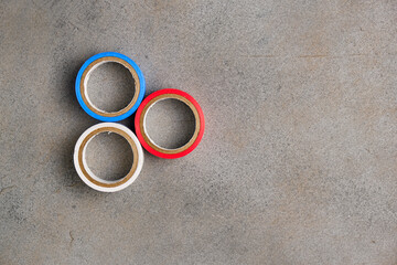 Multicolored electrical tape on an abstract gray background. White, blue, and red duct tape. Top view. Space for lettering and design