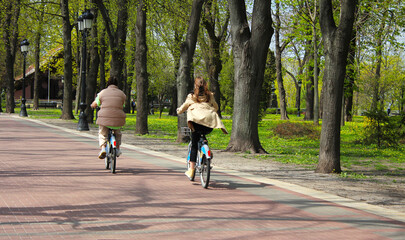 Girls ride a bike in the park.