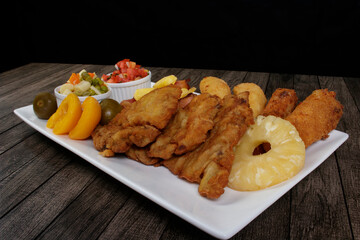 Traditional Cuban filet. Made with Breaded Steak, Banana, Breaded Cheese and Ham. French Fries with Bacon. Vegetables, and fruits. Served on the porcelain platter. Popular Brazilian cuisine.
