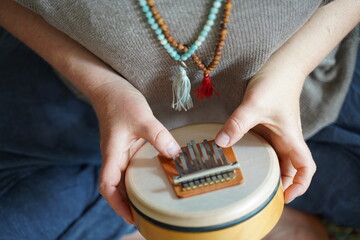 Woman holding and playing a sound healing instrument Sansula for sound healing therapy  - obrazy, fototapety, plakaty