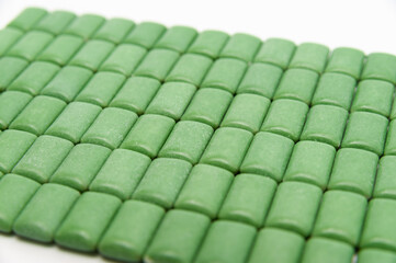 Obraz premium Green mint chewing gum tablets aligned. Isolated on white background. Close-up.